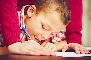 Enfant faisant ses devoirs avec l'aide d'un bénévole